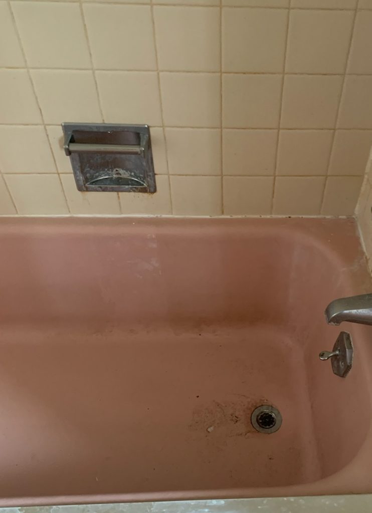 Pink bathtub before cleaning, with grime and stains