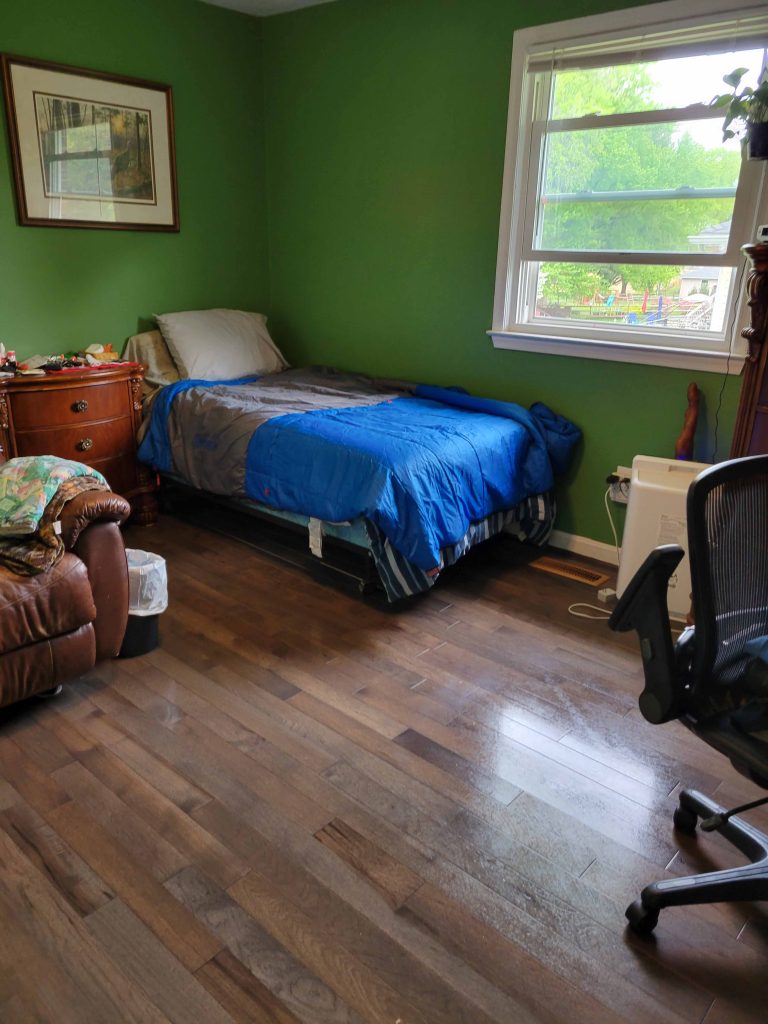 Same bedroom after cleaning, bed made and floor clear