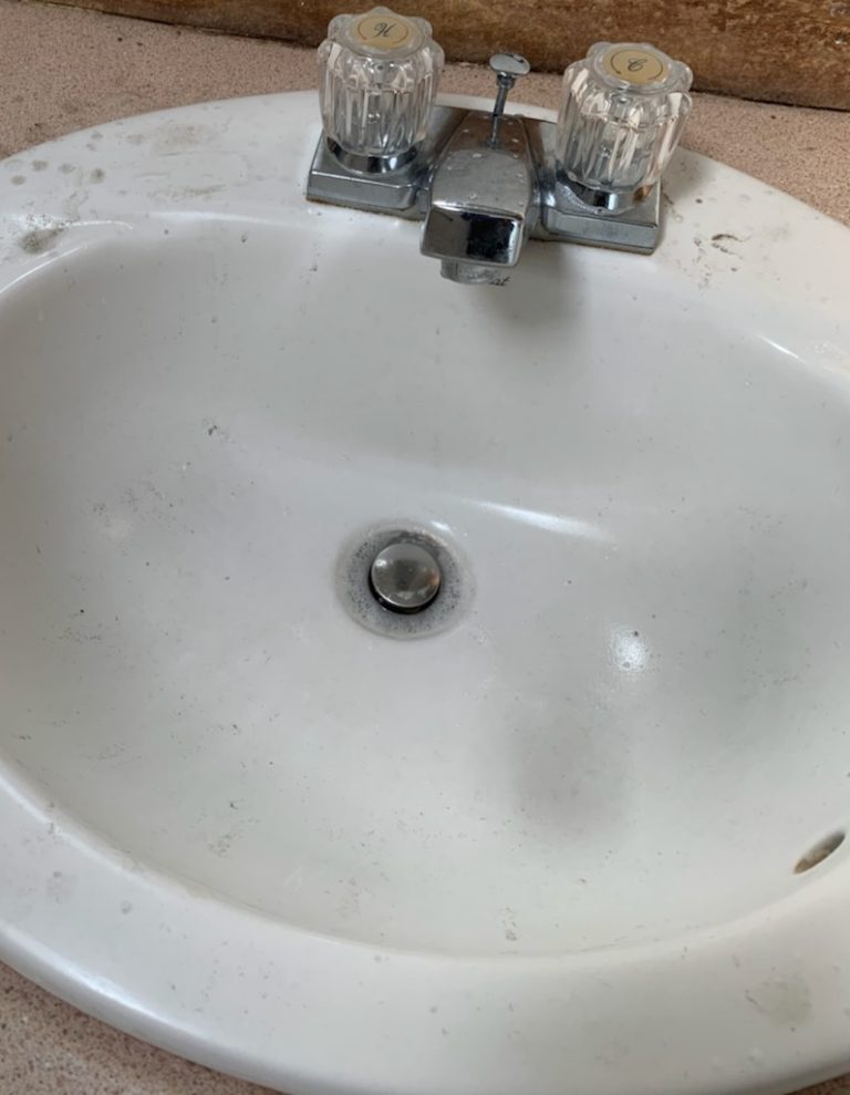 Bathroom sink before cleaning, with residue in the basin
